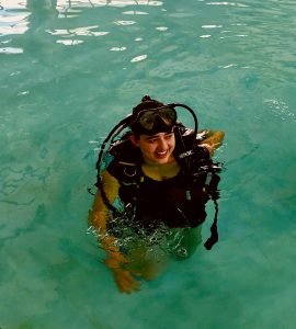 Mia is pictured floating in a pool of turquoise water, wearing scuba gear.