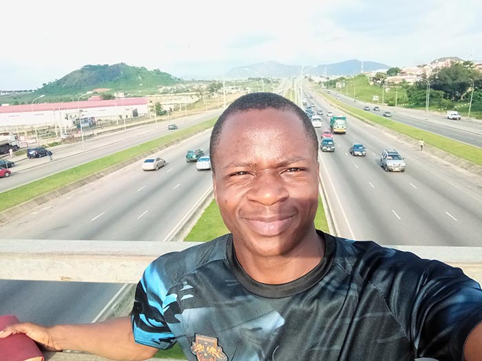 Ademiku takes a selfie while standing on a motorway bridge in his home country of Nigeria
