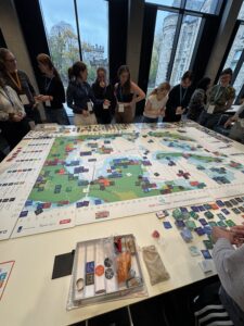 A group of people standing around a games board on a table