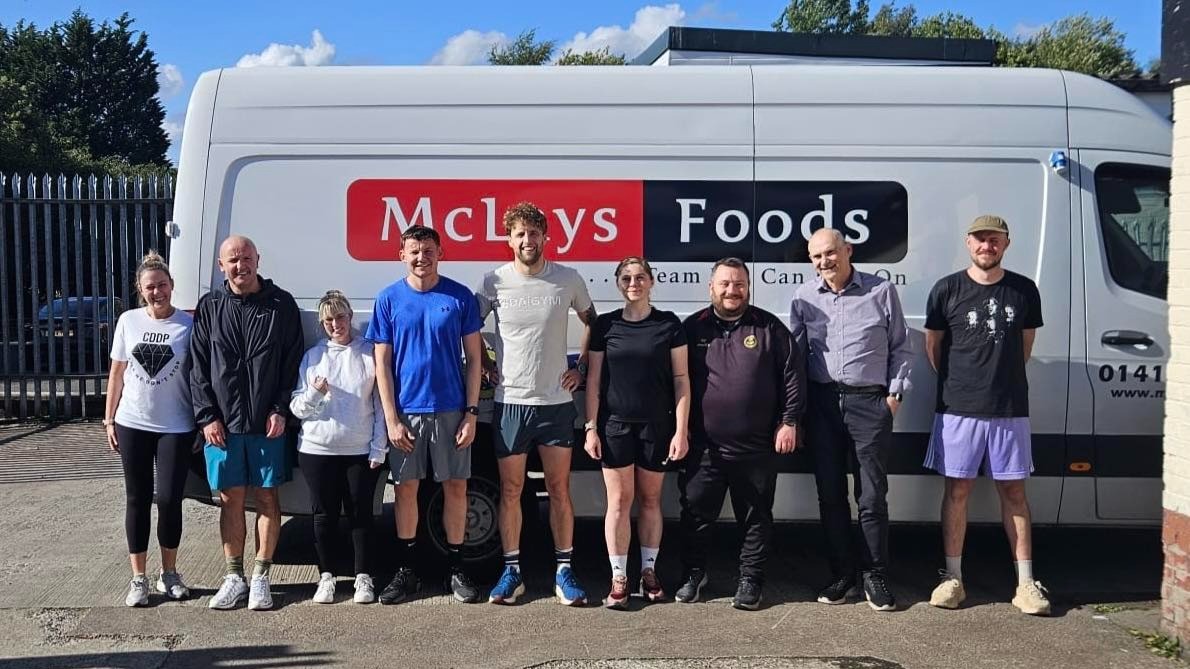 A group of people stand in front of a McLays delivery van