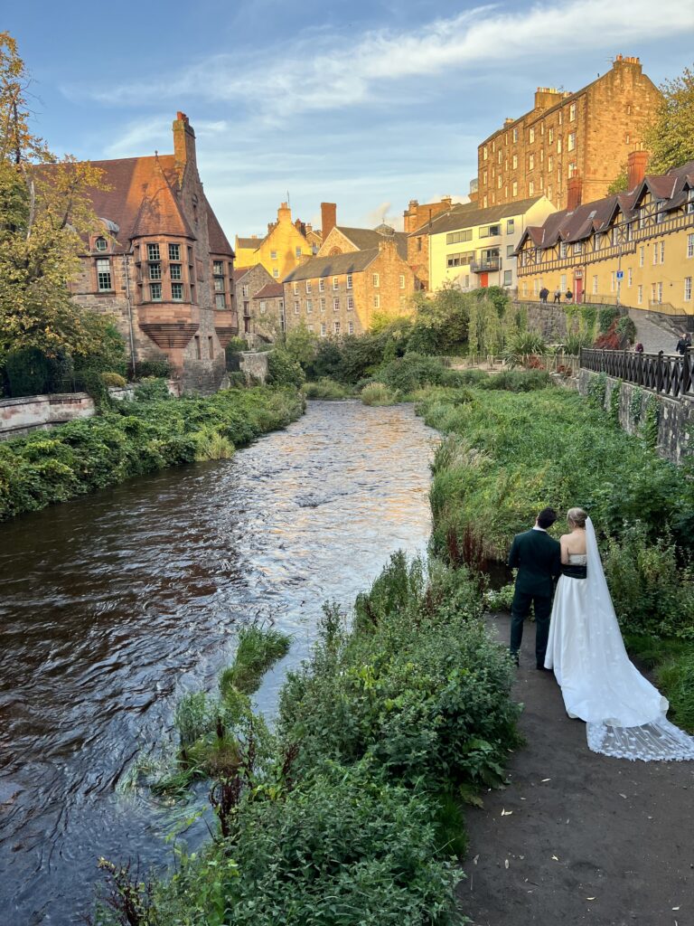 A bride and groom are pictured standing next to the river flowing through Dean Village