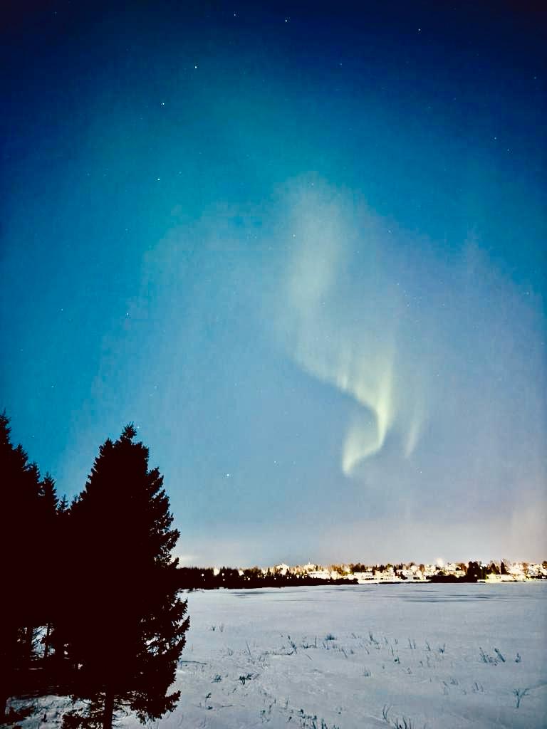The Aurora Borealis is captured in the sky above a frozen lake.