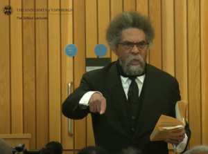 Professor Cornel West giving his lecture, holding a book