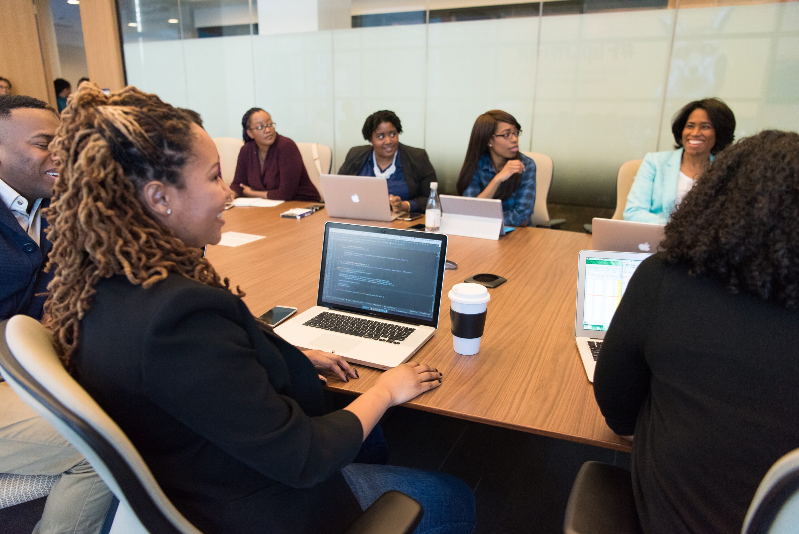 People sitting around a board table with laptops