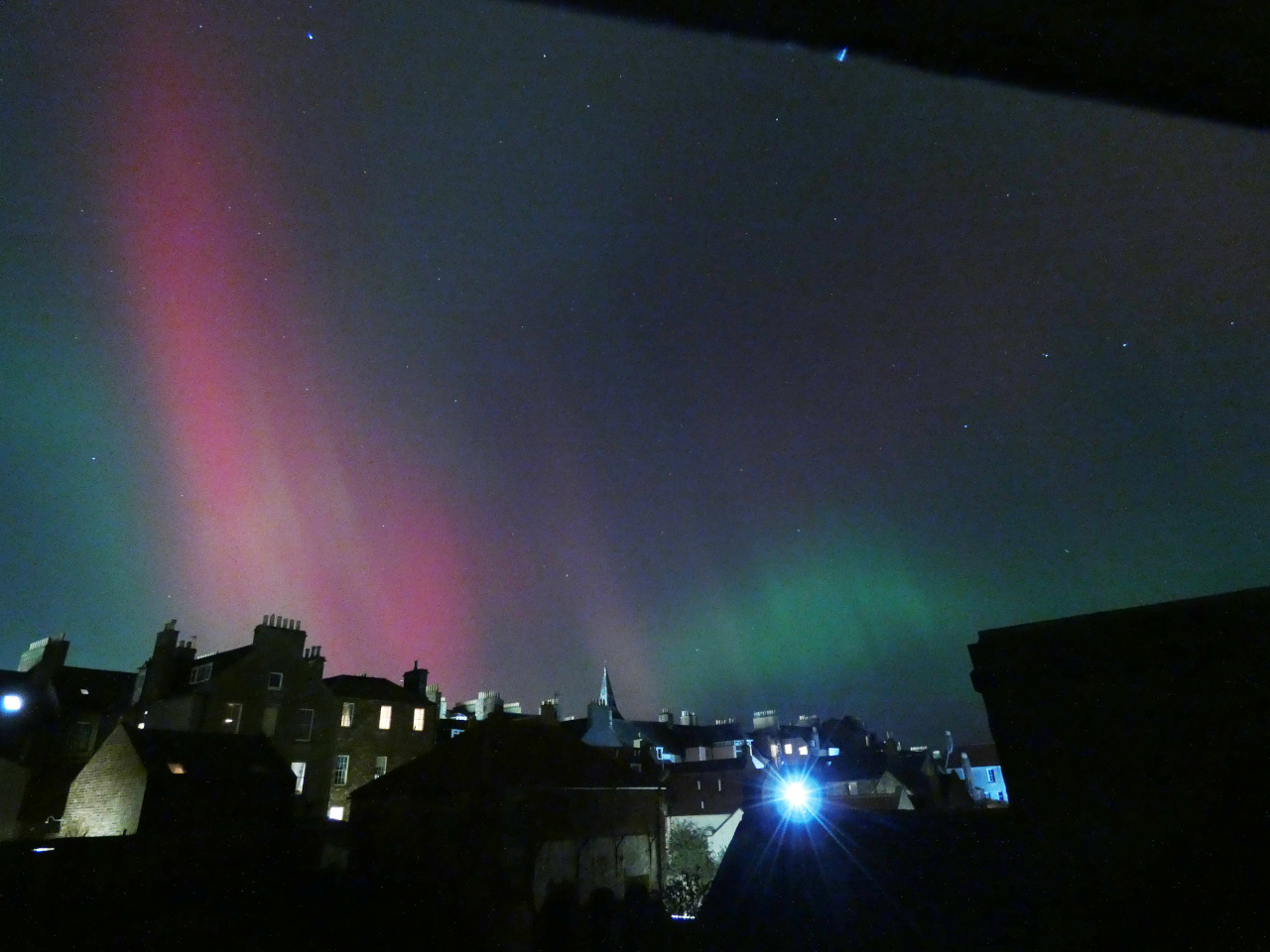 Town skyline with pink and green glowing sky