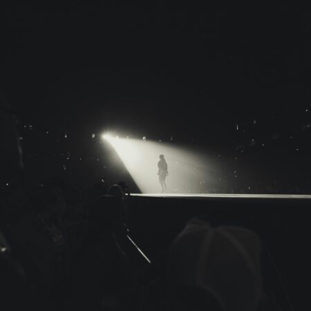 Black and white photo of someone on a stage in spotlight.