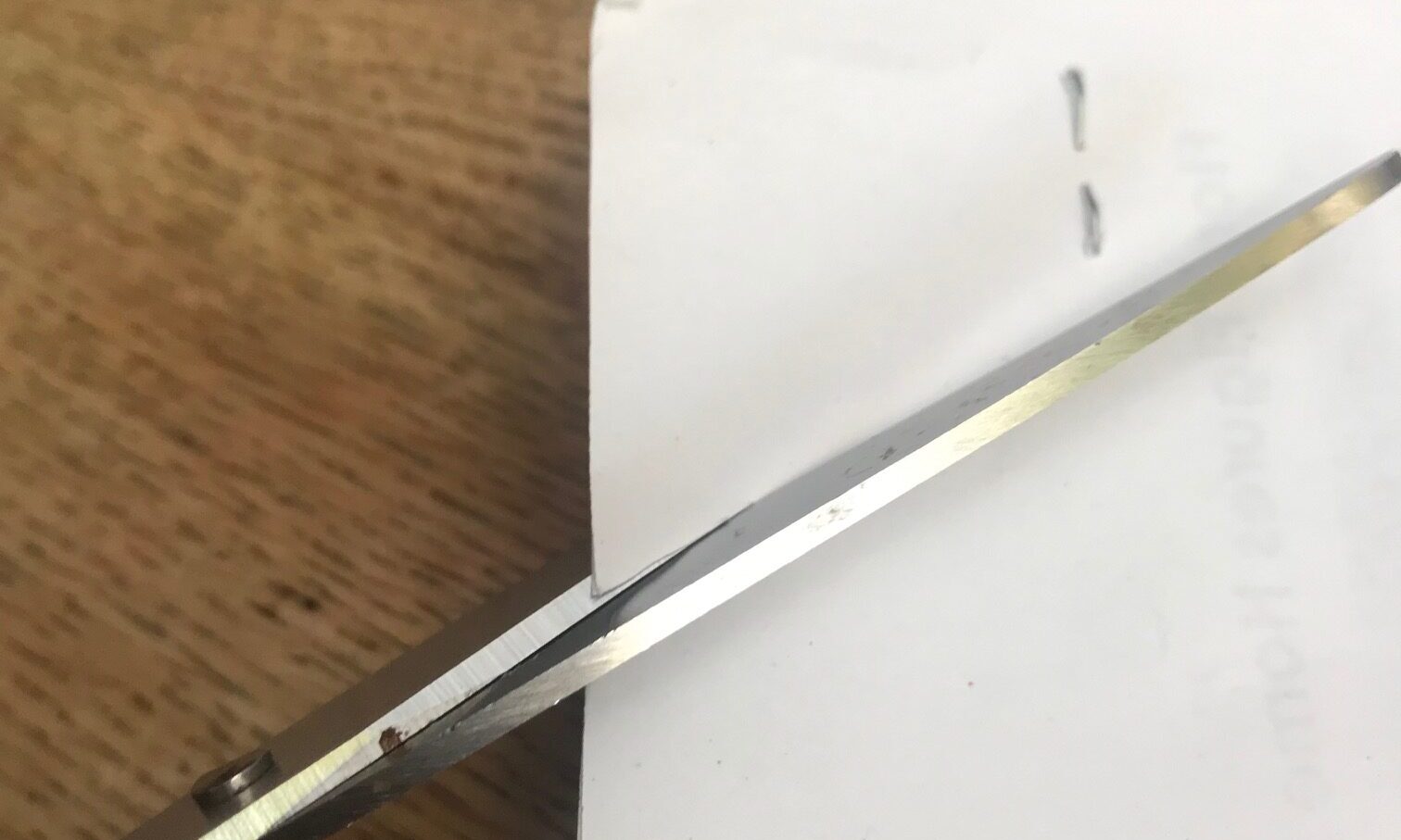 photo of scissors cutting the corner of a piece of white paper
