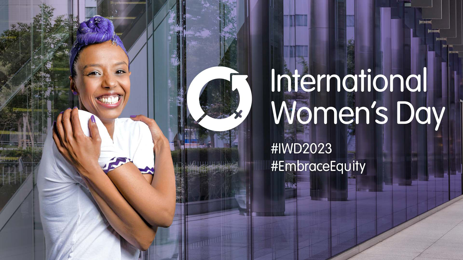 Smiling woman, hugging herself. Text: International Women's Day, #WD2023, #EmbraceEquity.