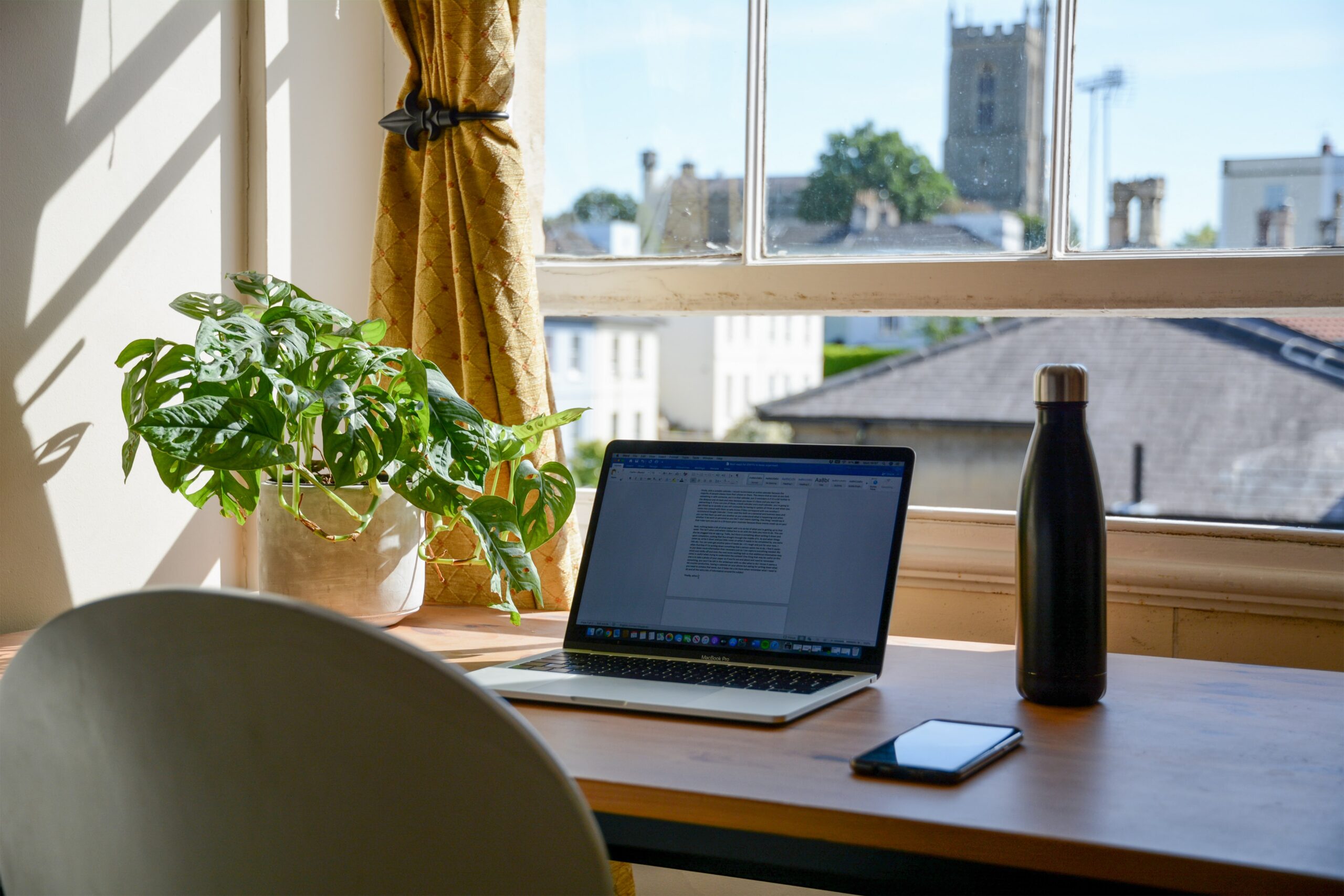 Desk with laptop, mobile phone and water bottle.