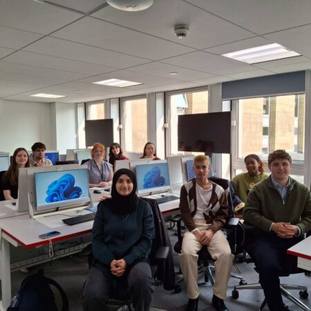 Group of interns sat beside computers in an Argyle House training room.
