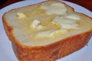 A picture of a thick slice of white bread with melted butter on it