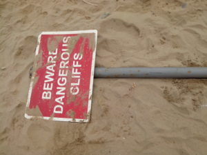 a dangerous cliff warning sign... that has fallen off a dangerous cliff