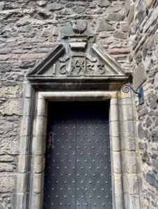 Photo of doorway to Acheson House, with the icon of a cockerel standing on a trumpet carved above.