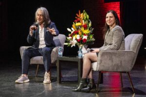 Two people in chairs with a flower arrangement between them