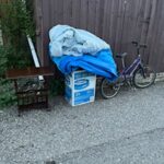 Three give away items in the alley including a side table, an inflatable pool, and a child's bike.