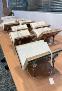 Rare books stand on plastic stands, which have been re-used and adapted for this exhibition