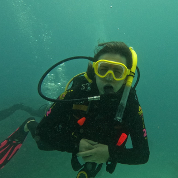 Hannah wearing black wetsuit and yellow snorkel under the water