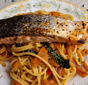 Portion of fish with noodles and vegetables on a plate