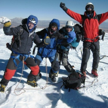 Group of 4 people in outdoor clothing on snowy moutain.