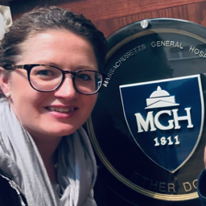 Rachael wearing a scarf and glasses beside a sign for Massachusetts General Hospital.