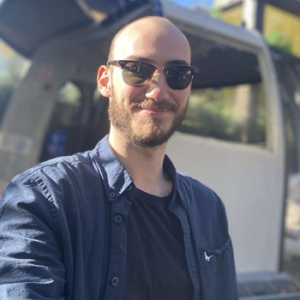 Portrait of medical student, Joe sitting outside wearing sunglasses.