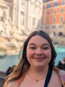 Image of Sarah smiling looking into camera in front of a fountain