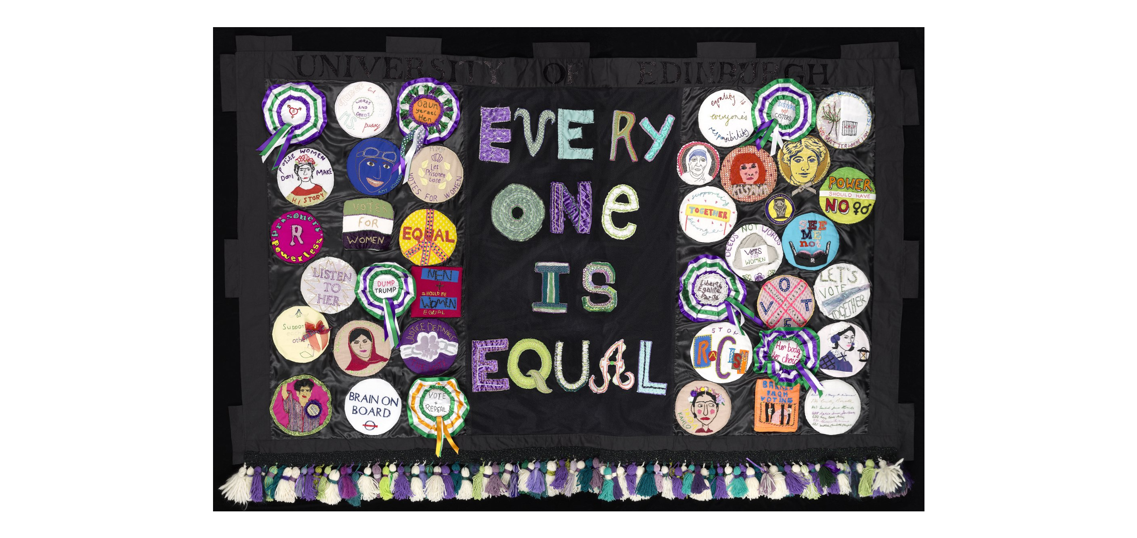 A black fabric banner with the words 'Every one is Equal' written down the centre with one word on each line. To either side of the words there are a number of fabric badges representing different messages about equality.