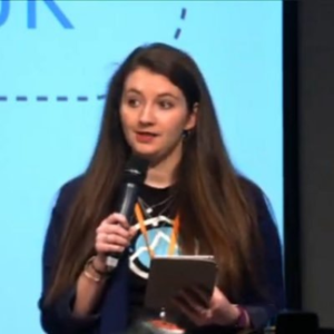 Kirsten Leggatt holding a microphone, talking at an event