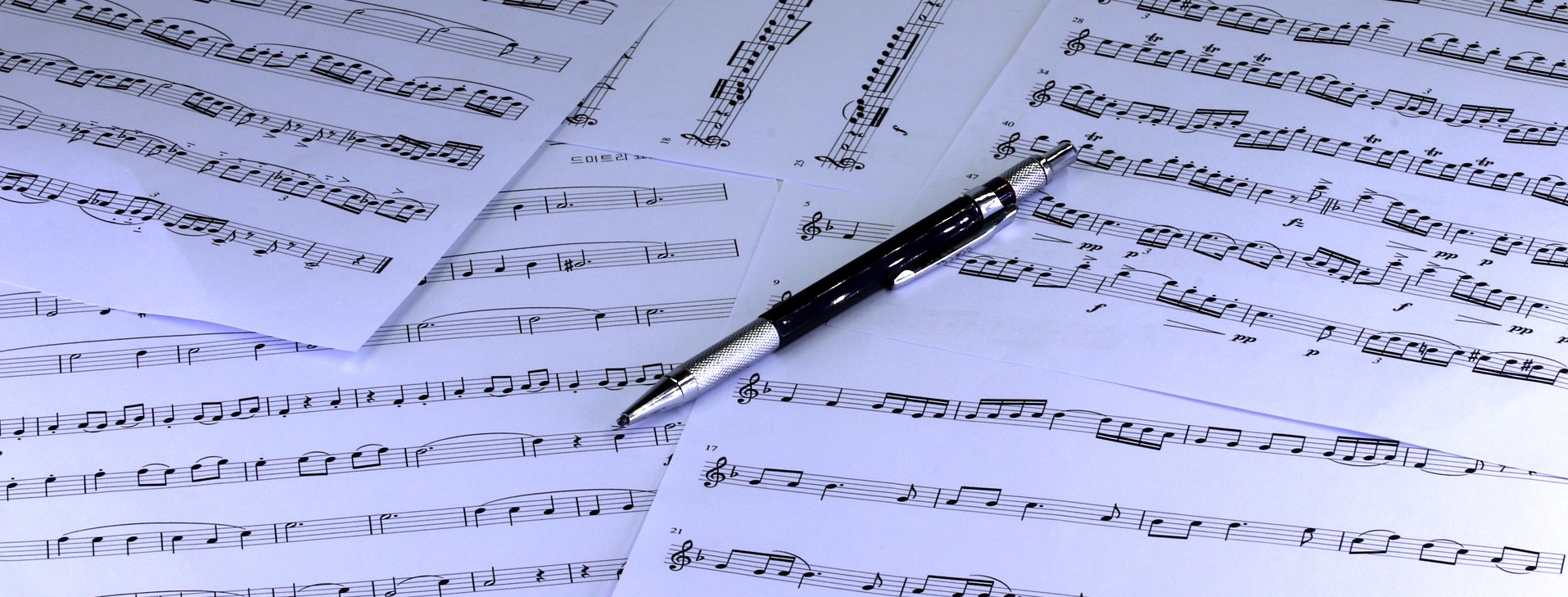 Sheet music with black pen lying on top.