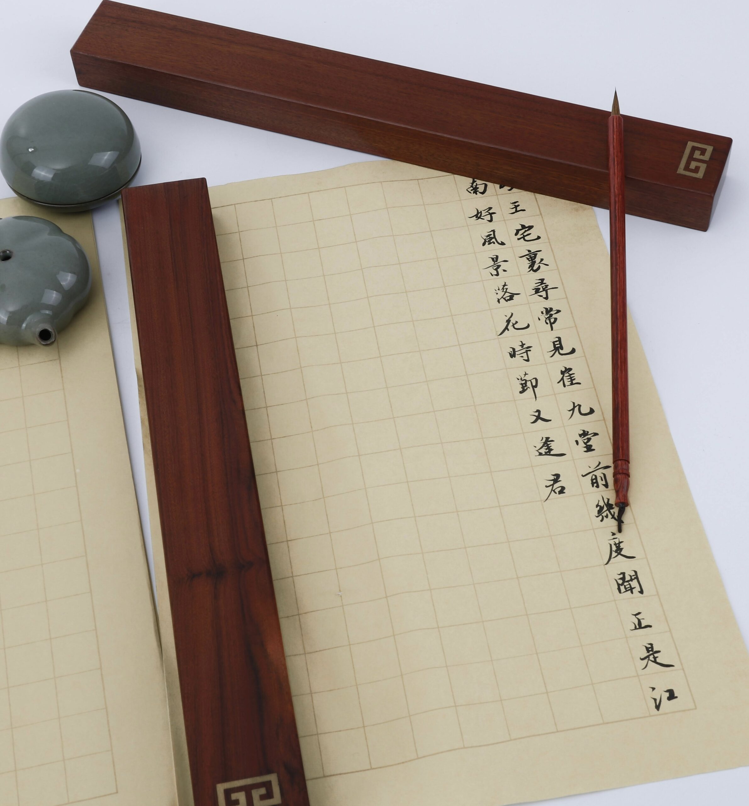 A brush is placed on the utensil of traditional Chinese calligraphy, with exquisite Chinese characters written on the grid paper below