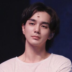This is a close-up photo of a Korean actor. The actor in the photo is wearing a white shirt.