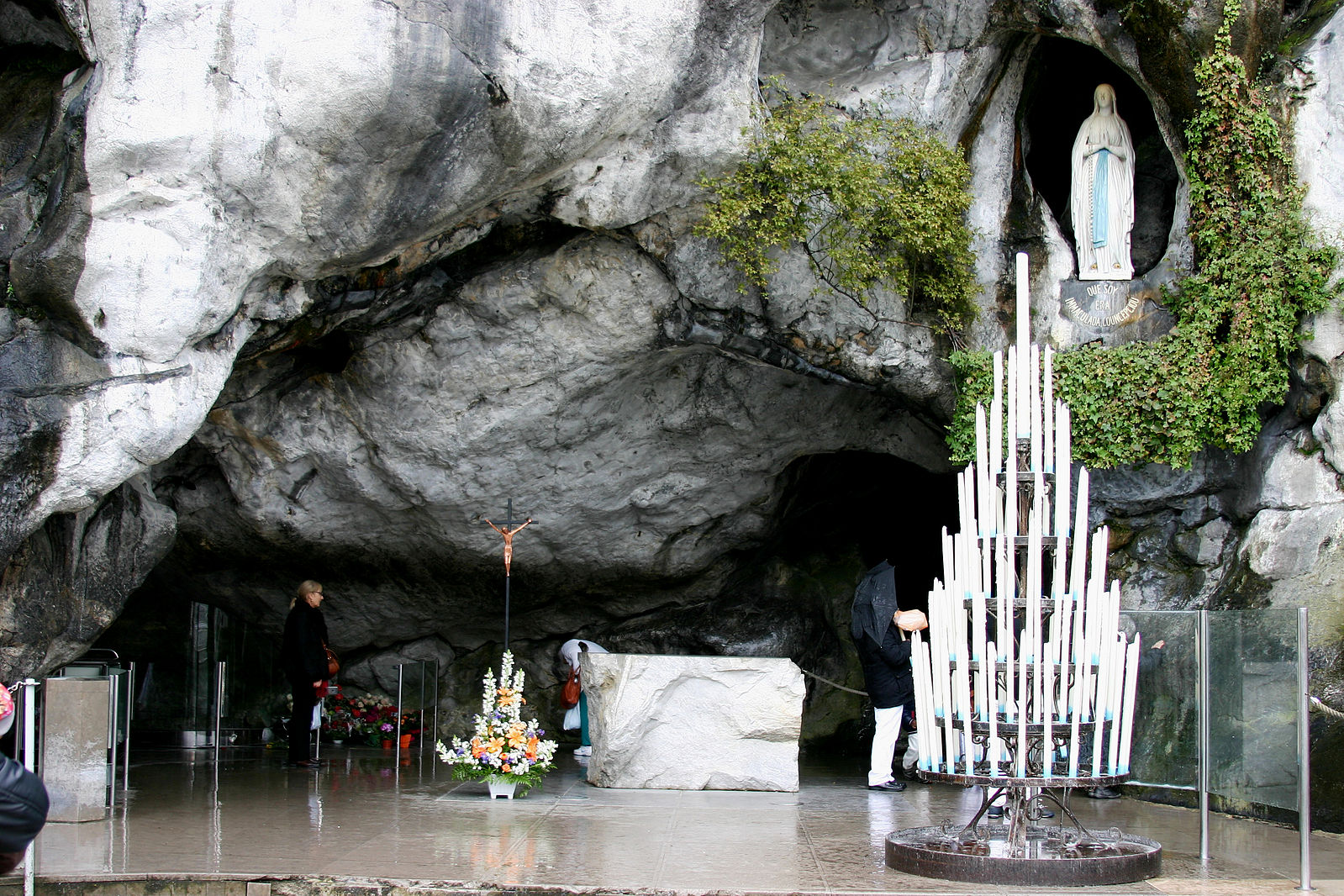 Grotto with a religious statue and large candle stand.