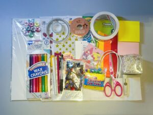 This is a tiled map filled with handmade materials, used as an example. It contains: white cardboard, stickers in the shape of stars and hearts, colored paper, sticky notes, colored crayons, colored threads, sequins, colored wool balls, scissors, knives, pearl strings, tape, ribbons, black pens.