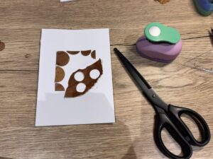 Use white glue to attach polka dot-shaped leaves to form a square around the leaves, creating an artwork.