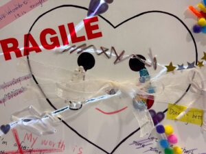 This is a photograph of the completed, repaired work held against a light source. Light shines brightly through the cracks and repair lines, suggesting that our mended cracks can shine brilliantly when viewed from a different perspective.