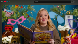 YouTube video screenshot of Nicola Coughlan reading "Carla’s Glasses" on Storyline Online, with colourful props and book in hand.