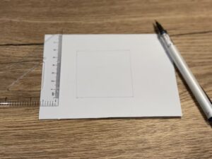 Use a ruler and mechanical pencil to draw a square on a blank postcard.
