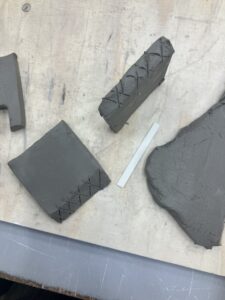 One side of each clay square has been cut diagonally and crosshatched, ready for joining. 