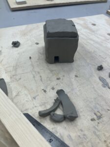 The clay roof has been roughly placed upon the four clay walls.