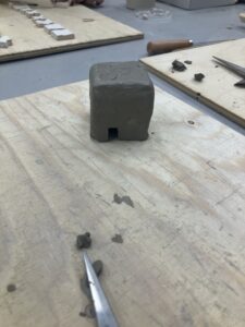 A moulded and shaped rudimentary ceramic house structure. 