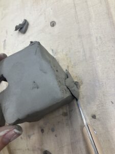 The top of the ceramic structure is being cut down to remove excess clay.