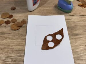 Use white glue to attach a leaf shape that is missing a few dots to the bottom right corner of a blank postcard.