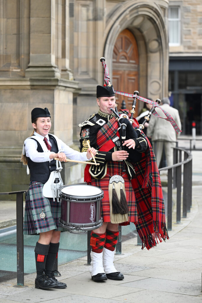 A piper and a drummer in highland dress outside the McEwan Hall.