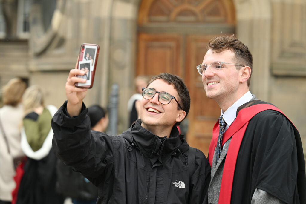 A graduate getting a selfie in front of the McEwan Hall