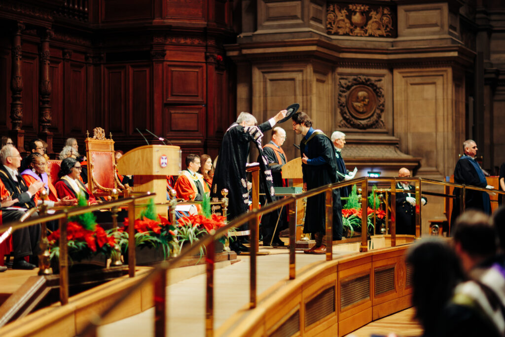 Professor Sir Peter Mathieson, Principal and Vice Chancellor, places the Graduation Cap over the head of a new graduate.