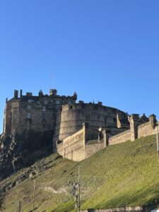 Edinburgh Castle on a grassy hill, set against blue sky