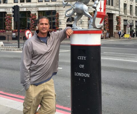 Man leaning on statue of a dragon that reads 'city of london'