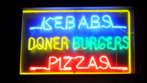 A glowing neon fast food restaurant sign contributes to our desire to eat fast food after a drunken night out.