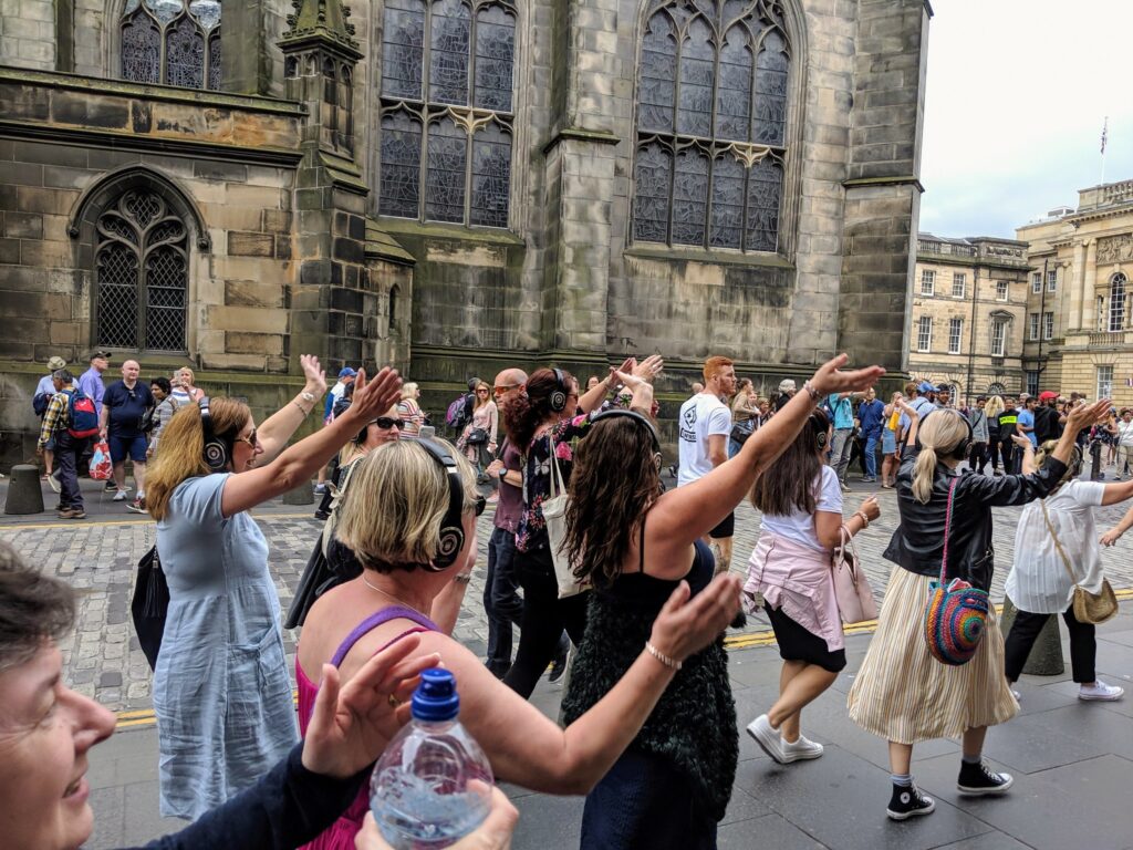 Women dancing with headphones in street in Edinburgh