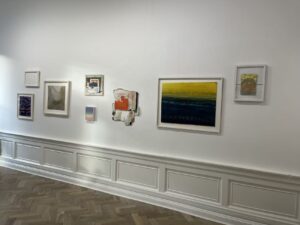 Several contemporary paper art pieces are hanging on a white wall.